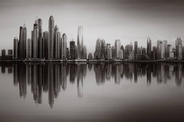 Tek renkli şehir gökdelenleri bulutlu bir gökyüzü altında sakin suyu yansıtan gökdelenler, kentsel gelişim konsepti, Dubai Marina Körfezi BAE