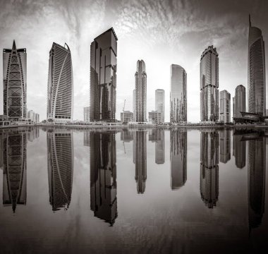 Tek renkli şehir gökdelenleri bulutlu bir gökyüzü altında sakin suyu yansıtan gökdelenler, kentsel gelişim konsepti, Dubai Marina Körfezi BAE