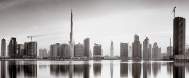 Tek renkli şehir gökdelenleri bulutlu bir gökyüzü altında sakin suyu yansıtan gökdelenler, kentsel gelişim konsepti, Dubai Marina Körfezi BAE