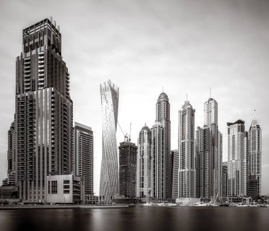 Gökdelenler ve su üzerindeki köprü, siyah-beyaz tarzı, şehir arkaplanı, şehir gelişimi konsepti, Dubai Marina körfezi BAE