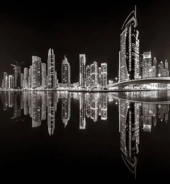 Aydınlatılmış gökdelenleri ve gece siyah beyaz rıhtımlı şehir silüeti, kentsel gelişim konsepti, Dubai Marina Körfezi BAE