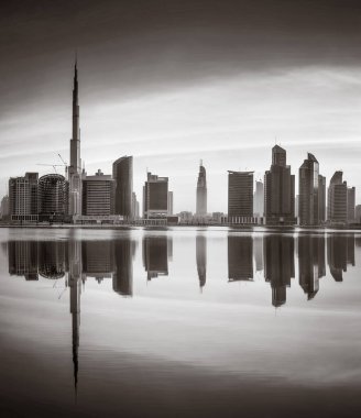 Tek renkli şehir gökdelenleri bulutlu bir gökyüzü altında sakin suyu yansıtan gökdelenler, kentsel gelişim konsepti, Dubai Marina Körfezi BAE