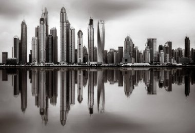 Tek renkli şehir gökdelenleri bulutlu bir gökyüzü altında sakin suyu yansıtan gökdelenler, kentsel gelişim konsepti, Dubai Marina Körfezi BAE