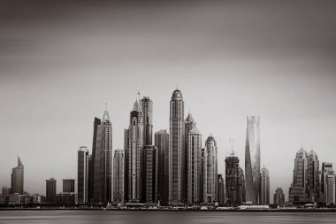 Tek renkli şehir gökdelenleri bulutlu bir gökyüzü altında sakin suyu yansıtan gökdelenler, kentsel gelişim konsepti, Dubai Marina Körfezi BAE