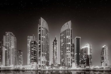 Aydınlatılmış gökdelenleri ve gece siyah beyaz rıhtımlı şehir silüeti, kentsel gelişim konsepti, Dubai Marina Körfezi BAE