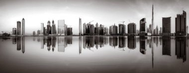 Tek renkli şehir gökdelenleri bulutlu bir gökyüzü altında sakin suyu yansıtan gökdelenler, kentsel gelişim konsepti, Dubai Marina Körfezi BAE