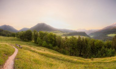 Berchtesgaden Ulusal Parkı, Yukarı Bavyera Alpleri, Almanya, Avrupa 'da gün batımında Hintersee Gölü yakınlarında yol ve bank ile Meadow. Gökyüzü yolu kırpılıyor