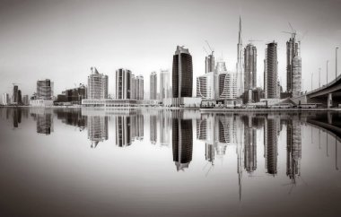 Tek renkli şehir gökdelenleri bulutlu bir gökyüzü altında sakin suyu yansıtan gökdelenler, kentsel gelişim konsepti, Dubai Marina Körfezi BAE