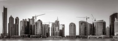 Tek renkli şehir gökdelenleri bulutlu bir gökyüzü altında sakin suyu yansıtan gökdelenler, kentsel gelişim konsepti, Dubai Marina Körfezi BAE