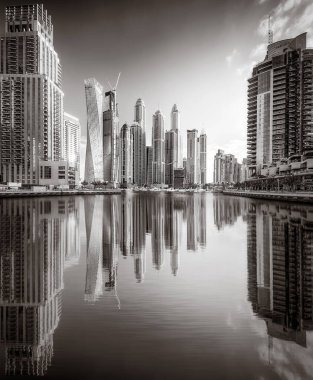 Tek renkli şehir gökdelenleri bulutlu bir gökyüzü altında sakin suyu yansıtan gökdelenler, kentsel gelişim konsepti, Dubai Marina Körfezi BAE