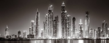 Aydınlatılmış gökdelenleri ve gece siyah beyaz rıhtımlı şehir silüeti, kentsel gelişim konsepti, Dubai Marina Körfezi BAE