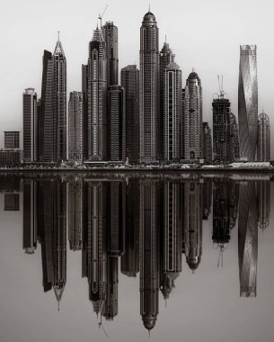 Tek renkli şehir gökdelenleri bulutlu bir gökyüzü altında sakin suyu yansıtan gökdelenler, kentsel gelişim konsepti, Dubai Marina Körfezi BAE