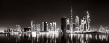 Aydınlatılmış gökdelenleri ve gece siyah beyaz rıhtımlı şehir silüeti, kentsel gelişim konsepti, Dubai Marina Körfezi BAE