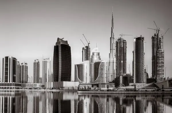 Tek renkli şehir gökdelenleri bulutlu bir gökyüzü altında sakin suyu yansıtan gökdelenler, kentsel gelişim konsepti, Dubai Marina Körfezi BAE