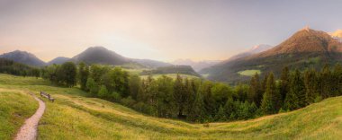 Berchtesgaden Ulusal Parkı, Yukarı Bavyera Alpleri, Almanya, Avrupa 'da gün batımında Hintersee Gölü yakınlarında yol ve bank ile Meadow. Gökyüzü yolu kırpılıyor