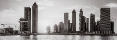 Tek renkli şehir gökdelenleri bulutlu bir gökyüzü altında sakin suyu yansıtan gökdelenler, kentsel gelişim konsepti, Dubai Marina Körfezi BAE