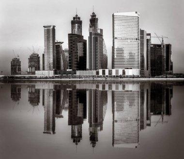 Tek renkli şehir gökdelenleri bulutlu bir gökyüzü altında sakin suyu yansıtan gökdelenler, kentsel gelişim konsepti, Dubai Marina Körfezi BAE