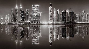 Aydınlatılmış gökdelenleri ve gece siyah beyaz rıhtımlı şehir silüeti, kentsel gelişim konsepti, Dubai Marina Körfezi BAE