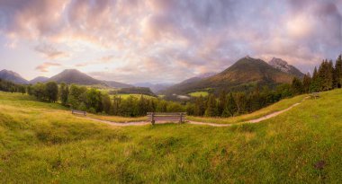 Berchtesgaden Ulusal Parkı, Yukarı Bavyera Alpleri, Almanya, Avrupa 'da gün batımında Hintersee Gölü yakınlarında yol ve bank ile Meadow. Gökyüzü yolu kırpılıyor