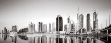 Gökdelenler ve su üzerindeki köprü, siyah-beyaz tarzı, şehir arkaplanı, şehir gelişimi konsepti, Dubai Marina körfezi BAE