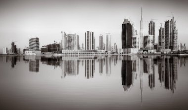 Tek renkli şehir gökdelenleri bulutlu bir gökyüzü altında sakin suyu yansıtan gökdelenler, kentsel gelişim konsepti, Dubai Marina Körfezi BAE