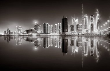 Aydınlatılmış gökdelenleri ve gece siyah beyaz rıhtımlı şehir silüeti, kentsel gelişim konsepti, Dubai Marina Körfezi BAE