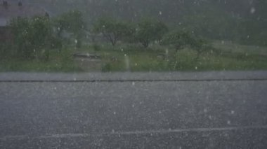 Hailstones fall heavily on the driveway and field during a severe storm