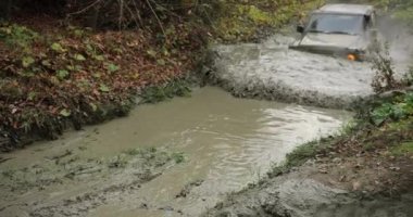 Bir SUV yüksek hızda off-road 'da su birikintisine doğru gidiyor..