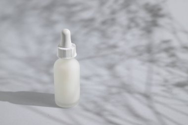 Beyaz cam kozmetik şişesi gölgede