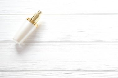 Beyaz şık parfüm şişesi ahşap masanın üstünde.