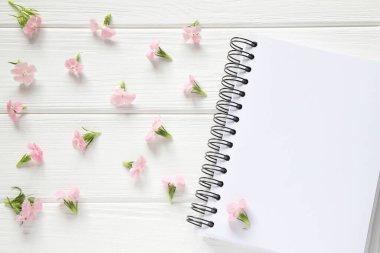 Tahta masada pembe çiçekli boş defter, maket.