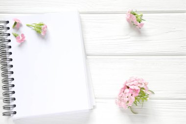 Tahta masada pembe çiçekli boş defter, maket.