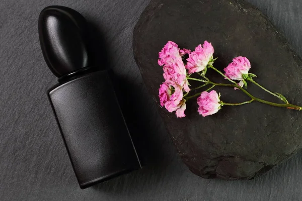 Parfümflasche Aus Schwarzem Glas Und Rosa Blumen Auf Steinhintergrund Attrappe — Stockfoto