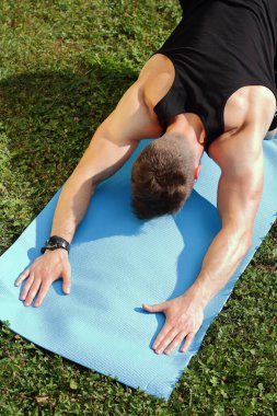 Yeşil çimlerde yoga yapan bir adam parkta, açık hava eğitiminde.