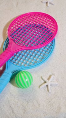 Plaj tenisi seti, raket ve top kumsalda.