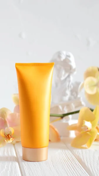 Mockup cream tube, yellow blank bottle and orchid flower, place for text