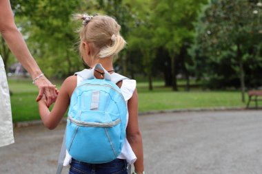 Pupil girl child with backpack going to school on the street