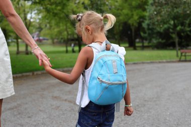 Pupil girl child with backpack going to school on the street