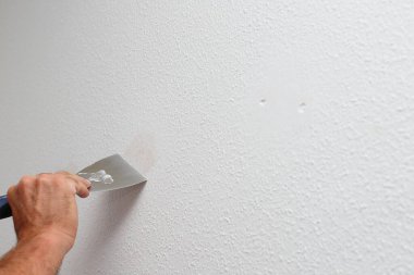 Tavandaki çatlakları tamir eden işçiler, mala kullanarak alçıyı yayıyorlar, evi yeniliyorlar.