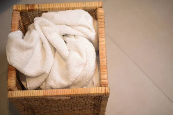 Dirty laundry in wooden box, towels in bathroom