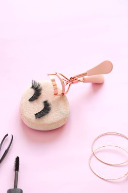 Renkli arka planda pembe kirpikli saç maşası ve takma göz kirpikleri