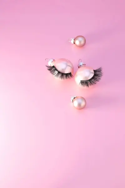 Noel ağacı süslemesinde sahte kirpikler, pembe arka plan.