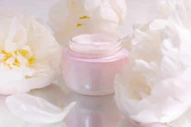 Kozmetik krem kavanozu maketi ve çiçekler, cilt bakımı konsepti