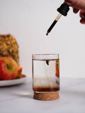 Doğal kahverengi takviyeler. Sıvı vitaminler bir bardak suya pipetli, yaşam tarzlı.