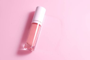 Çiçekli gül arkaplanlı dudak parlatıcı tüp, makyaj malzemesi.