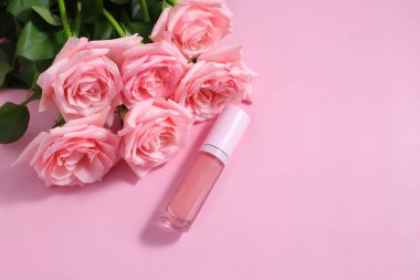 Çiçekli gül arkaplanlı dudak parlatıcı tüp, makyaj malzemesi.