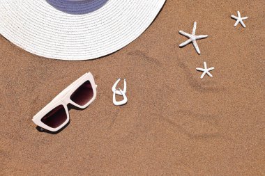 Güneş gözlüğü, şapka ve küpeler kumsalda deniz kabukları, plaj aksesuarları