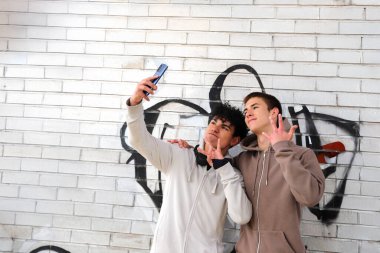 Teknoloji ve gençler, dışarıda akıllı telefonla selfie çeken iki genç çocuk.