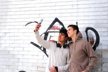 Teknoloji ve gençler, dışarıda akıllı telefonla selfie çeken iki genç çocuk.