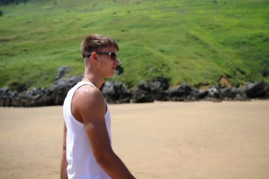 Plajda güneş gözlüklü genç, sıradan bir genç, yaz yaşam tarzı.